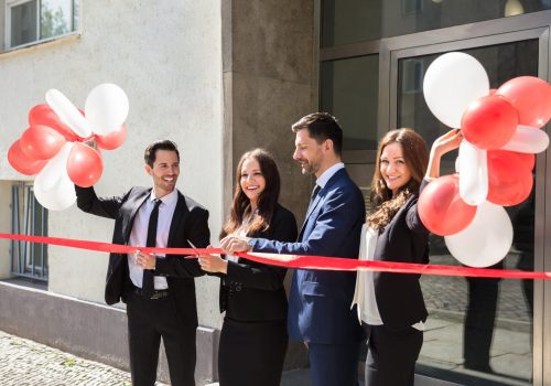 Businesspeople Cutting Red Ribbon